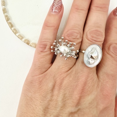 Anéis de prata com pérola e conchas na mão de uma pessoa