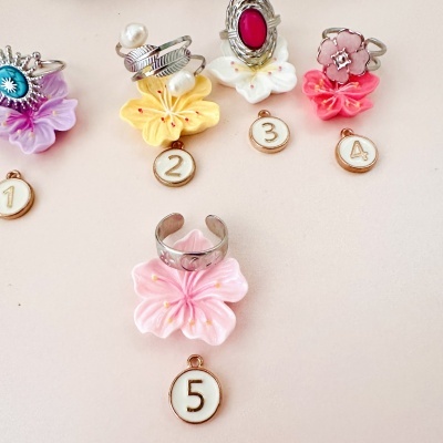 Anéis variados com flores coloridas e etiquetas numeradas em fundo bege