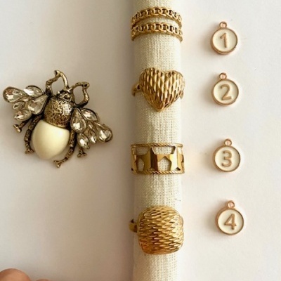 joia abelha metálica dourada, quatro anéis dourados com texturas, etiquetas numeradas 1 a 4