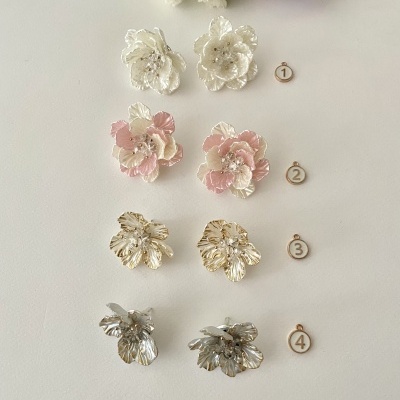 Quatro pares de brincos florais em branco, rosa, dourado e prateado organizados verticalmente com números ao lado