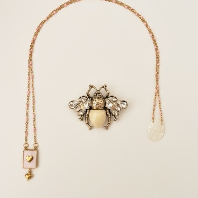Colar com pingente retangular rosa e broche de inseto dourado com pedras