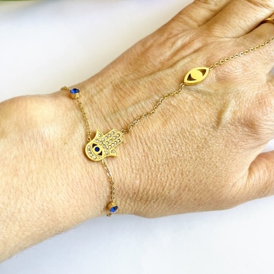 pulseira dourada com pendente mão de Fátima e olho azul no pulso