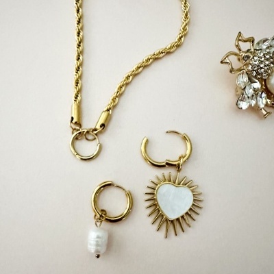 Colar dourado com corrente torcido e dois brincos dourados com pendentes coração e pérola