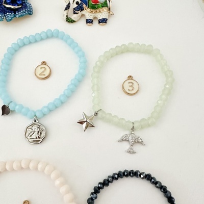 Pulseiras de contas coloridas com pendentes metálicos e etiquetas numeradas