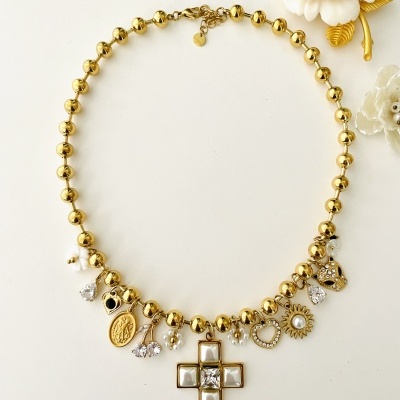 Colar dourado com pendentes variados sobre superfície branca