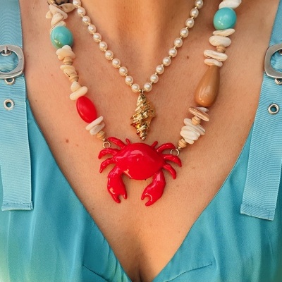 Colar com pingentes de caranguejo vermelho e concha dourada em camisa azul