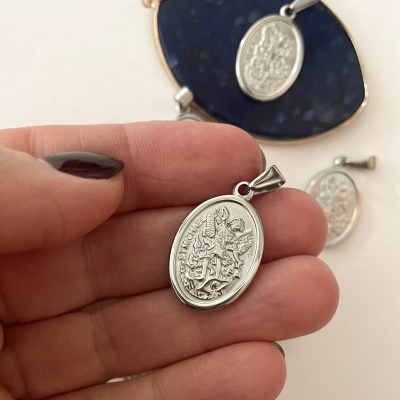 Medalha oval em metal prateado detalhada com figuras