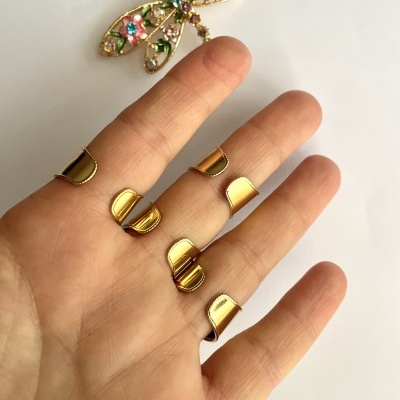 Mão com anéis dourados nas juntas dos dedos e broche de libélula colorido ao fundo