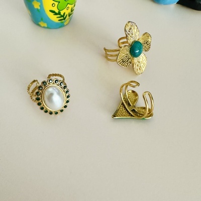 Três anéis dourados sobre superfície branca com pedras e detalhes distintos