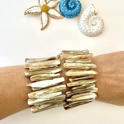 Bracelete de madrepérola em braço com broches em forma de flor e conchas