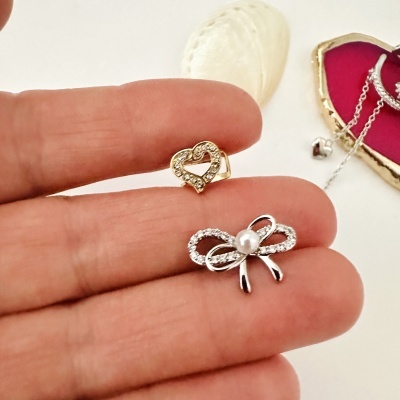 Anéis pequenos dourado e prateado com brilhantes em forma de coração e laço