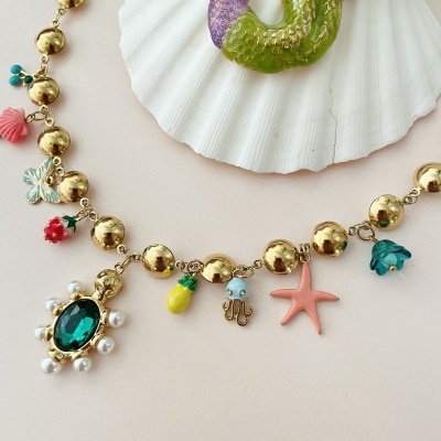 Colar dourado com pendentes coloridos e concha branca