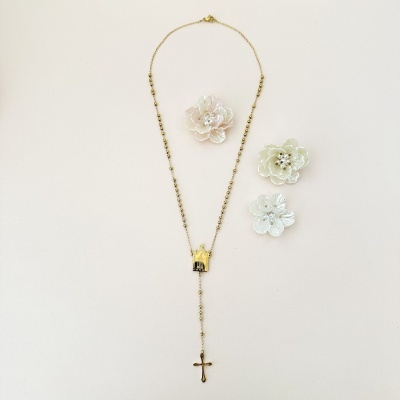 Colar dourado com crucifixo e três flores decorativas claras ao lado