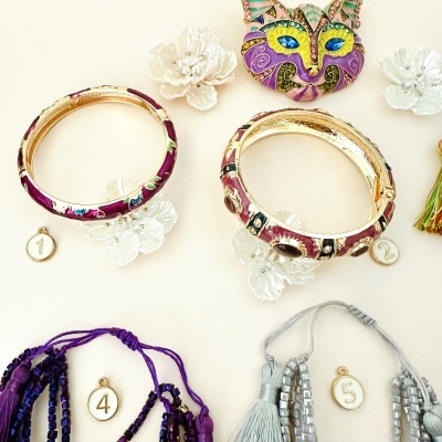 Pulseiras e colares coloridos com contas, números e flores brancas em fundo claro