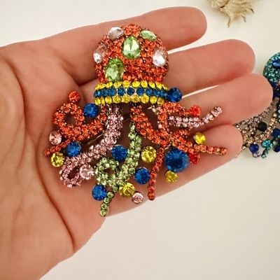 Broche colorido em forma de polvo com pedras brilhantes em várias cores