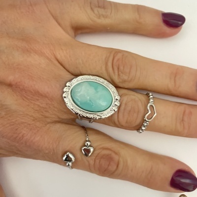Mão com três anéis em prata com pedra azul e corações