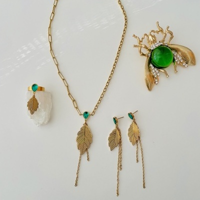 Conjunto de joias douradas com pedras verdes e detalhes em forma de folha e inseto
