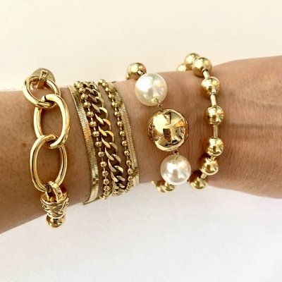 Pulseiras douradas variadas num pulso