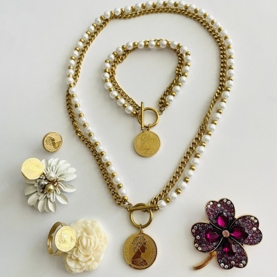 Conjunto de bijuterias douradas com pérolas e acessórios florais em fundo branco