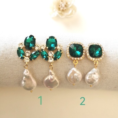 Dois pares de brincos com pedras verdes e pérolas penduradas sobre tecido bege