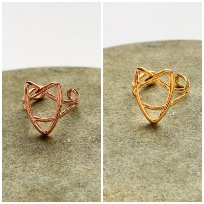 Dois anéis em forma de raposa, um cobre e um dourado, sobre superfície cinzenta.