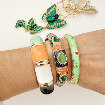 Pulseiras coloridas usadas no pulso com broches de borboletas verdes no fundo