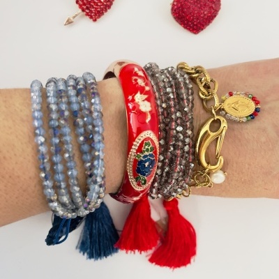 Pulso com várias pulseiras coloridas e dois pins de coração sobre fundo branco