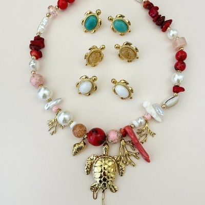 Colar colorido com contas e pendentes de tartaruga dourada e brincos de tartaruga em tons turquesa, castanho e branco.