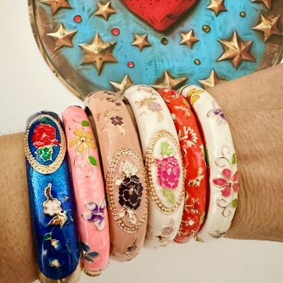 Pulseiras coloridas de cerâmica com padrões florais e acabamentos dourados no pulso