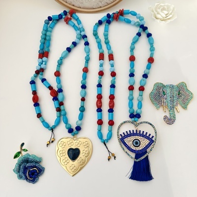 Colares com pedras azuis e pendentes distintos: coração dourado, olho azul e broches de rosa e elefante brilhantes