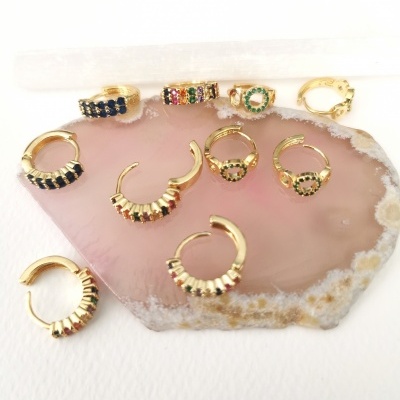 Brincos dourados com pedras coloridas sobre pedra decorativa