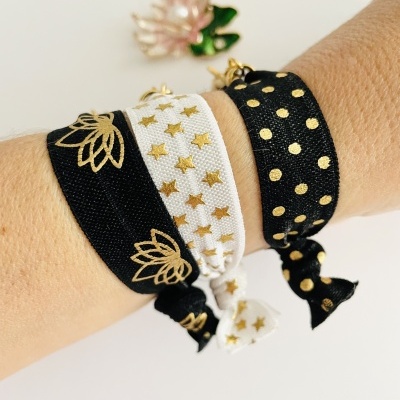Pulseiras de tecido com padrões dourados em preto e branco num pulso