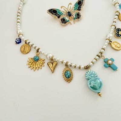 Colar de pérolas com pendentes dourados e azuis sobre fundo branco