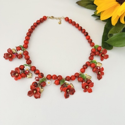 Colar com contas vermelhas, flores vermelhas e brancas e folhas verdes com fundo branco