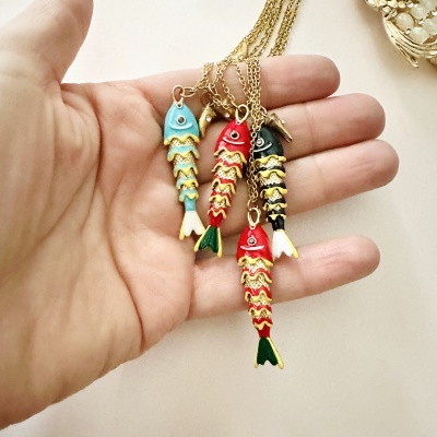 Colares pendentes em forma de peixe coloridos sobre mão