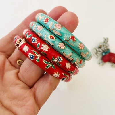 Três pulseiras esmaltadas com padrão floral colorido numa mão