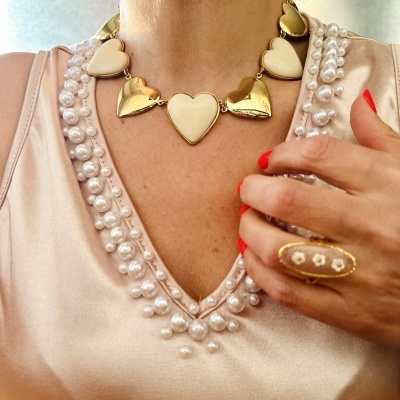 Colar de corações dourados e creme com camisa bege bordada com pérolas