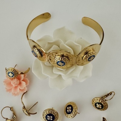 Conjunto de bracelete e brincos dourados com detalhes azuis e flores artificiais