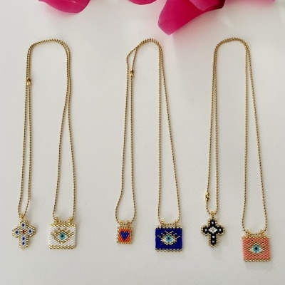 Cinco colares dourados com pendentes de contas coloridas e flores cor de rosa em fundo branco