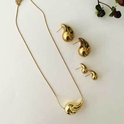 Conjunto de joalharia dourada com colar e dois pares de brincos ondulados