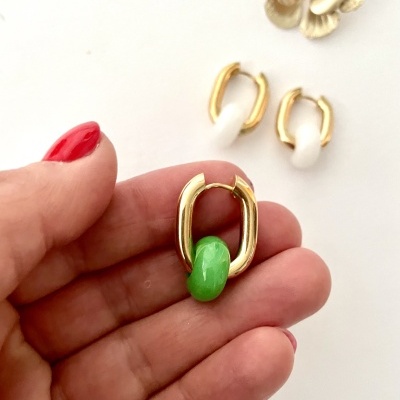 Brinco oval dourado com pedra verde, outros brincos em fundo branco