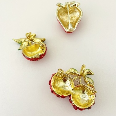 Brincos de frutos vermelhos com folhas douradas em fundo branco