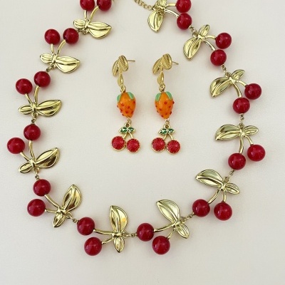 Conjunto colar e brincos dourados com contas vermelhas em forma de cereja e morango
