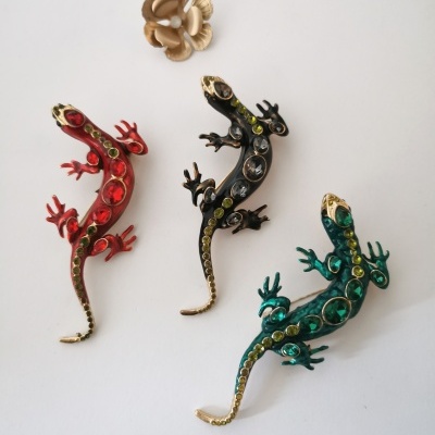 Três broches de lagarto coloridos com pedras e uma flor dourada metálica