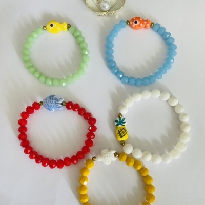 Pulseiras coloridas por conta e com pequenos pingentes de peixe, ananás, concha, estrela e cavalo-marinho
