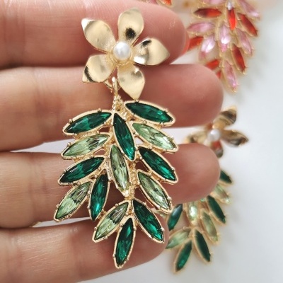 Brinco dourado com flor e folhas verdes com pérola no centro