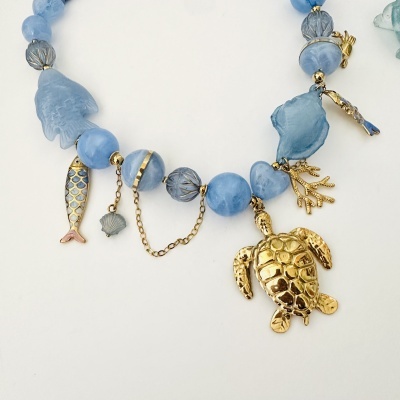 Colar azul com pendentes dourados de tartaruga, peixe e concha