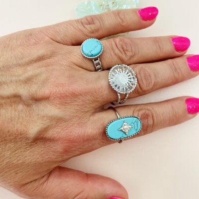 Mão com 3 anéis de prata com pedras turquesa e unhas pintadas cor rosa forte