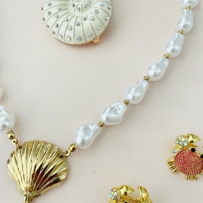 joias com concha dourada, contas peroladas e broches de caranguejo coloridos
