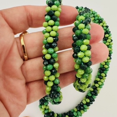 Colar de contas verdes facetadas em mão com anel dourado
